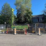 Photo of a sonic well drill rig with safety fencing in a residential neighborhood.